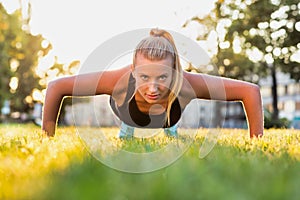 Portrait of young attractive woman planking in park with lens flare photo