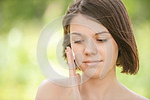 Portrait of young attractive woman putting cream on her face