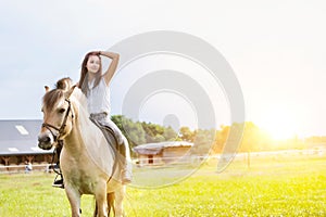 Portrait of young attractive woman riding horse in ranch