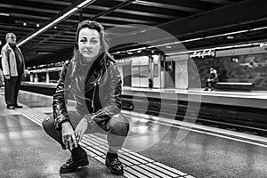 Portrait of young and attractive woman sitting in metro station.