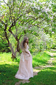 Portrait of young attractive woman walking in spring garden in sunny day. Spring background. Woman's Day