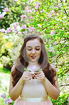 Portrait of young attractive woman walking in spring garden in sunny day. Spring background. Woman's Day