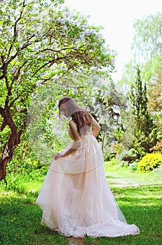 Portrait of young attractive woman walking in spring garden in sunny day. Spring background. Woman's Day