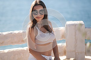 Portrait of young attractive woman in white clothes and sunglasses in front of beautiful sea. Vocation concept