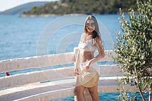 Portrait of young attractive woman in white clothes and sunglasses in front of beautiful sea. Vocation concept