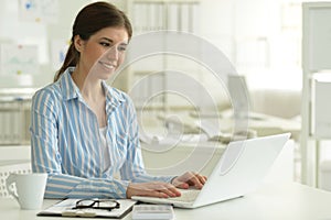 Portrait of young attractive woman working with laptop in office