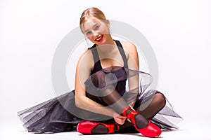 Portrait of young ballerina ballet dancer sitting on the floor and look at camera