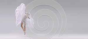 Portrait of young ballerina covered with white transparent fabric and dancing isolated over grey studio background