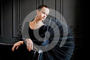 Portrait of young ballerina girl in black tutu on dark background