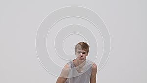 Portrait of young basketball player throwing the ball towards the camera. Athlete in sportswear posing against white