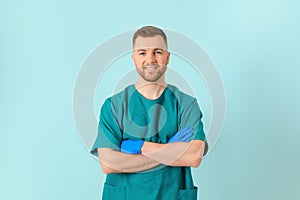 Portrait young bearded doctor with stethoscope over neck in medical coat standing against isolated blue background