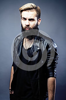 Portrait of young bearded hipster guy on gray dark background cl