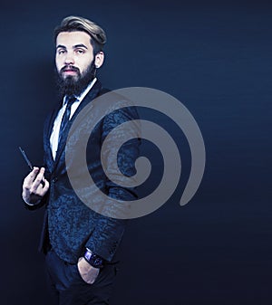 portrait of young bearded hipster guy on gray dark background close up, brutal modern man in suit, lifestyle people