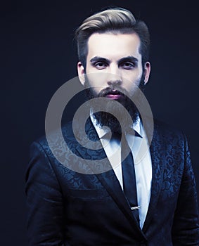 portrait of young bearded hipster guy on gray dark background close up, brutal modern man in suit, lifestyle people