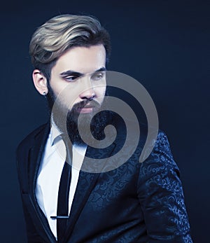 portrait of young bearded hipster guy on gray dark background close up, brutal modern man in suit, lifestyle people