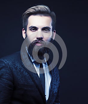 portrait of young bearded hipster guy on gray dark background close up, brutal modern man in suit, lifestyle people