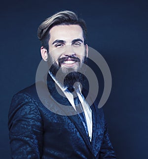 portrait of young bearded hipster guy on gray dark background close up, brutal modern man in suit, lifestyle people