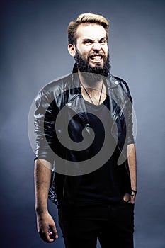 Portrait of young bearded hipster guy smiling on gray dark background close up, brutal modern man, lifestyle people