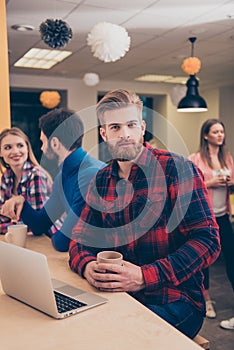 Portrait of young bearded manager with coffee having break on working project