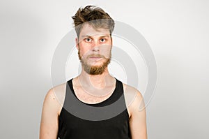 Portrait of young bearded unkempt scruffy man on gray background