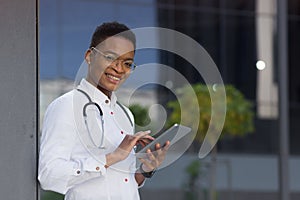 Portrait of young beautiful african american doctor woman smiling happy looking at camera and holding tablet, for patient