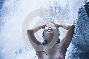 Portrait of young beautiful Asian girl looking pure and enjoying nature beauty with face wet under amazing beautiful natural water