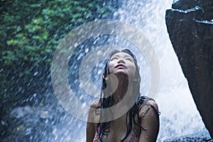 Portrait of young beautiful Asian girl looking pure and enjoying nature beauty with face wet under amazing beautiful natural water