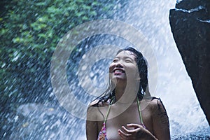 Portrait of young beautiful Asian girl looking pure and enjoying nature beauty with face wet under amazing beautiful natural water