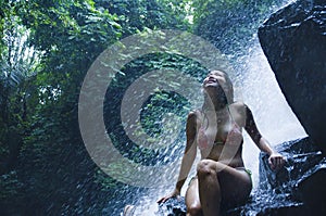 Portrait of young beautiful Asian girl looking pure and enjoying nature beauty with face wet under amazing beautiful natural water