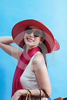 Portrait of young beautiful asian girl wearing white lady vest, sunglasses and sun hat holding shopping bags