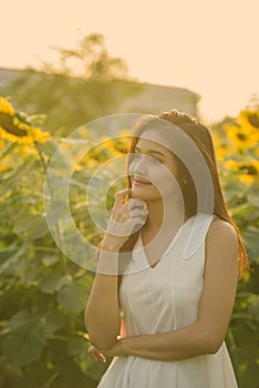 Young beautiful Asian woman thinking in the field of blooming sunflowers