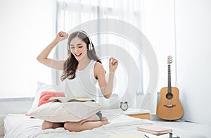 Portrait of young beautiful asian woman relax listen to music sing and dance from headphone in bedroom.