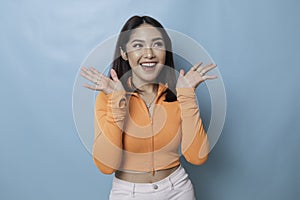 Portrait of Young beautiful Asian woman standing and smiling at the camera,  on blue background