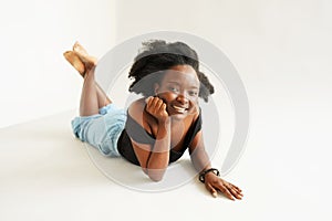 Portrait of a young beautiful black woman lied on the floor and smiling