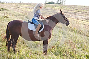 Portrait of young beautiful blond hair woman riding horse. Travel with animal