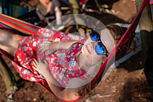 Portrait of young beautiful blonde cheerful girl enjoy in hammock outdoor. Relaxing in the hammock in the summer garden