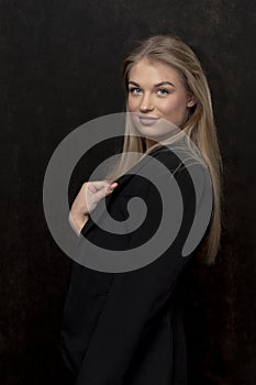 Portrait of a young beautiful blonde girl 20-25 years old on a dark background, close-up.