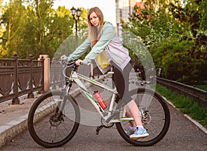 Portrait of young beautiful blonde girl with bicycle