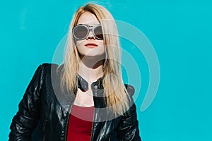 Portrait of a young beautiful blonde girl in huge sunglasses on the background of turquoise wall sunny summer day