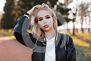 Portrait of a young beautiful blonde woman in a fashionable light black jacket in a stylish white shirt