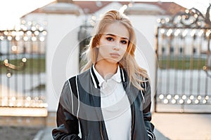 Portrait of a young beautiful blonde woman in a fashionable light black jacket in a stylish white shirt on the street
