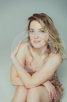 Portrait of a young beautiful blonde woman in a shiny golden dress. Girl with a beautiful smile