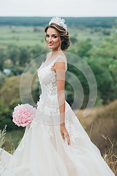 Portrait of a young beautiful bride on a background of a gorgeous view of the river and fields.