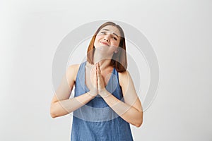 Portrait of young beautiful brunette girl praying over white background.