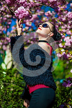 Portrait of young beautiful brunette near blooming sakura tree