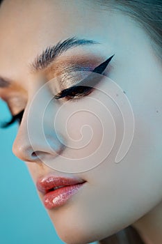 Portrait of a young beautiful brunette woman with bright eye makeup.