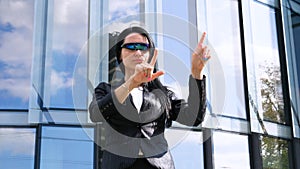 Portrait of young beautiful business woman student in suit, future glasses, smiling, successful looking at sides, with skyscrape