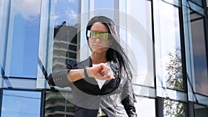 Portrait of young beautiful business woman student in suit, future glasses, smiling, successful looking at sides, with skyscrape