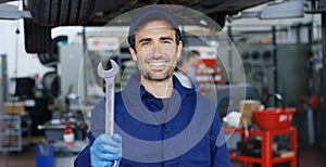 Portrait of a young beautiful car mechanic in a car repair shop, hands with a spanner. Concept: repair of machines, fault diagnosi