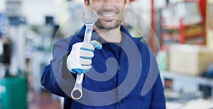 Portrait of a young beautiful car mechanic in a car repair shop, hands with a spanner. Concept: repair of machines, fault diagnosi